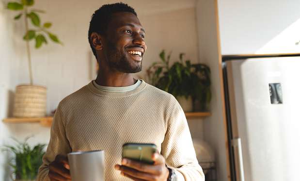 sexual-compulsions-and-addiction-2 Smiling man holding a mug and smartphone in a kitchen